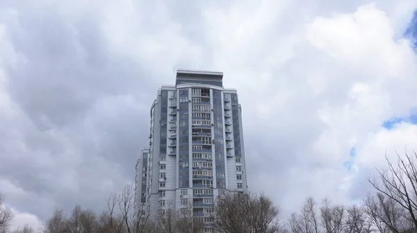 Höga hus. Vy av byggnaden från botten upp. Ovanför huset flytande tjocka grå moln — Stockfoto