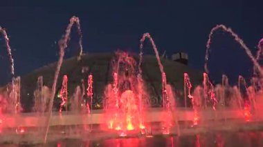 Gece-zaman şehir merkezinde çeşme. Su sonra tekrar falls yükselir. Çeşme ışıklar Parlatıcı farklı renklerde alt kısmında.