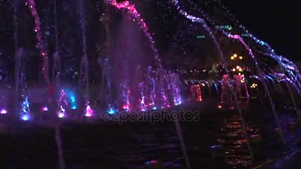 Fontana di notte in centro. Lenta acqua video poi si alza di nuovo cade. Nella parte inferiore della fontana le luci brillano in diversi colori . — Video Stock