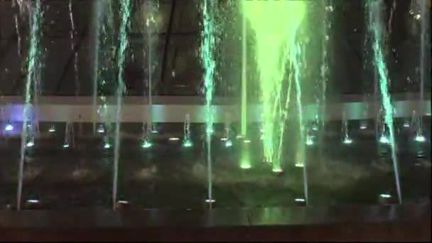Fontanna w nocy downtown. Następnie woda wznosi się ponownie go falls. Na dole fontanna światła lśnią w różnych kolorach. — Wideo stockowe