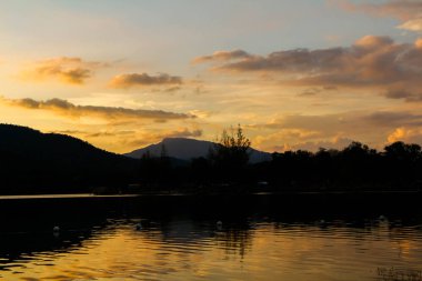Göl kenarında turuncu ve kırmızı günbatımı