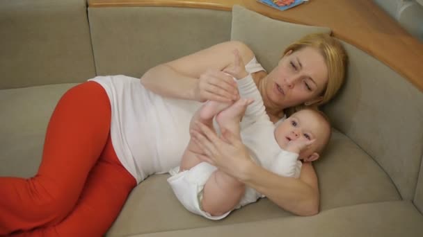40-jährige Mutter auf Sofa liegend mit lächelndem Baby