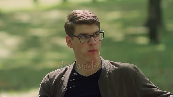 Young Cute Man Sitting On A Park Bench Eating A Big Apple Stock