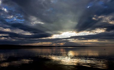 gri Bulutların arasından güneş göl üzerinde parlıyor