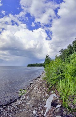 parlak mavi gökyüzü göl kıyısında üzerinde beyaz bulutlar ile