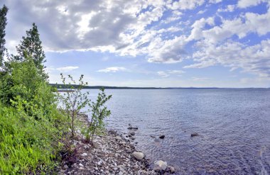 parlak mavi gökyüzü göl kıyısında üzerinde beyaz bulutlar ile