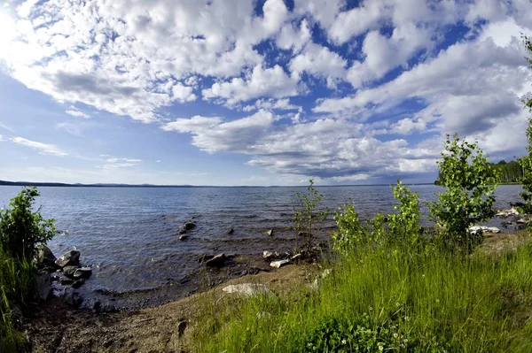 parlak mavi gökyüzü göl kıyısında üzerinde beyaz bulutlar ile