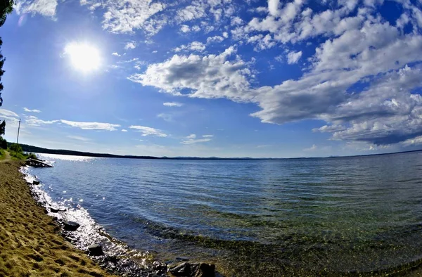 Jasně modré obloze s bílá mračna nad břehu jezera — Stock fotografie