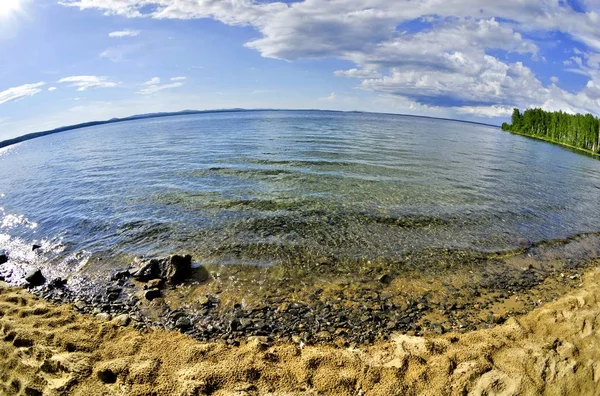 Céu azul brilhante com nuvens brancas sobre a costa do lago — Fotografia de Stock