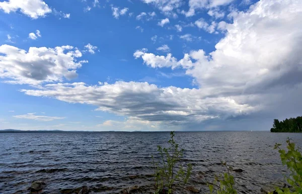 Ciel bleu vif avec des nuages blancs sur la rive du lac — Photo