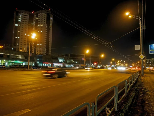 Upplyst stadsgata med rörliga bilar på vintern natt — Stockfoto