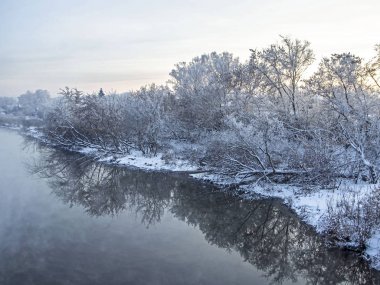 Kışın başlangıcında kırsal kesimde karla kaplı nehir kıyısı güney Urallar 'da soğuk bir kış akşamında görülüyor.