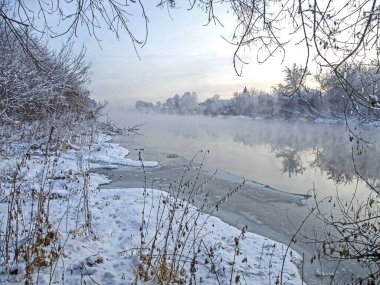 Kışın başlangıcında karla kaplı nehir kıyısında soğuk bir kış akşamı manzarası