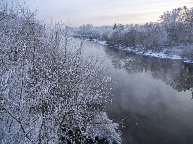 Kışın başlangıcında kırsal kesimde karla kaplı nehir kıyısı güney Urallar 'da soğuk bir kış akşamında görülüyor.