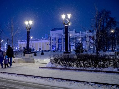 city street lights decorated in antique style on a winter night during a snowfall