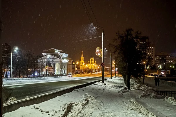Ночной зимней улице во время снегопада в городе с видом на органный зал и церковь Святой Троицы — стоковое фото