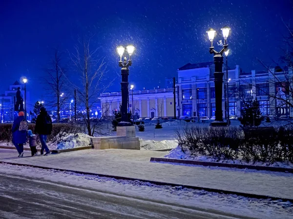 Luzes de rua da cidade decoradas em estilo antigo em uma noite de inverno durante uma queda de neve — Fotografia de Stock