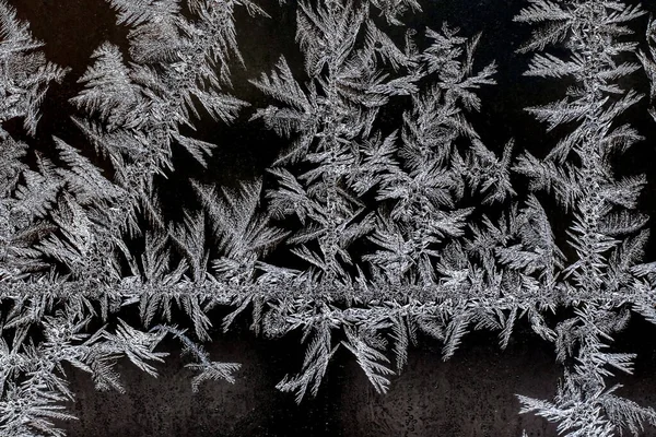 Frosty natural pattern on a winter window, texture of frosty patterns, dendritic image structure