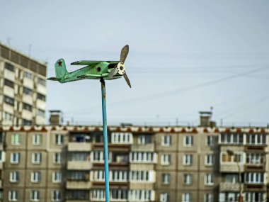 Rüzgar gülü eski bir uçak şeklindeydi. Sabah güneşiyle aydınlatılan çift kanatlı bir uçak.