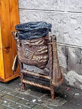 Demir bir süpürgeyle eski bir çöp torbası şeklinde neşeli bir çöp tenekesi.