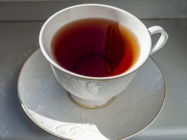Mug of fresh tea on the windowsill is illuminated by the sun — Stock Photo, Image