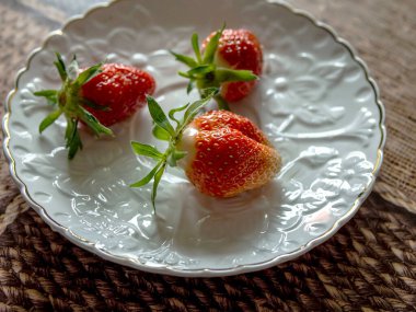 İlk taze, olgun çilek tabakta, yakın plan.