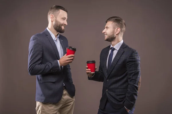 Two men standing with a cup of coffee