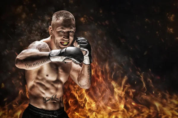 Mixed martial artist posing against the backdrop of fire and smoke. Concept of mma, ufc, thai boxing, classic boxing. Mixed media