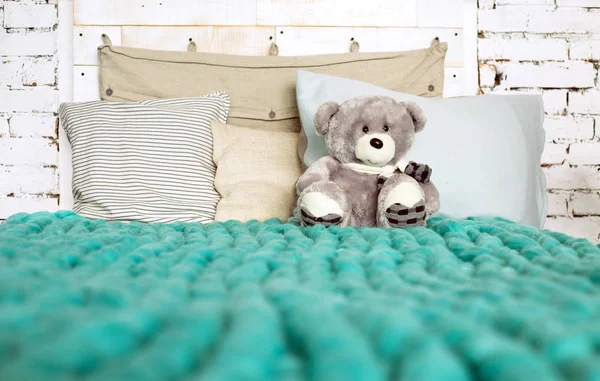 Koc z wełny Merino na łóżku z poduszkami w pastelowych kolorach i Ted — Zdjęcie stockowe