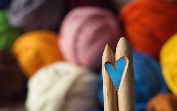 wooden knitting needles on background of colorful merino wool ba