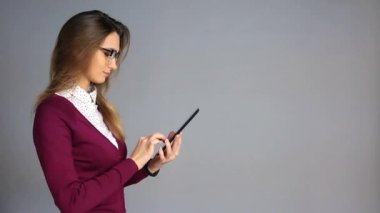 Güzel genç kadın gözlük ve iş rahat tarzı bir kopya alanı ile gri arka plan üzerinde tablet kullanma