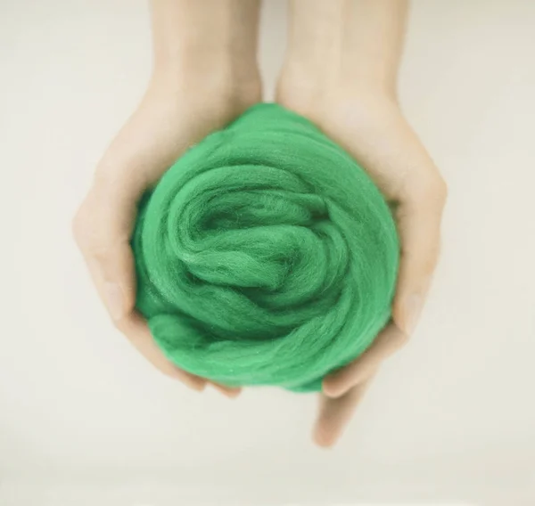 Close-up de bola de lã de merino verde em mãos — Fotografia de Stock