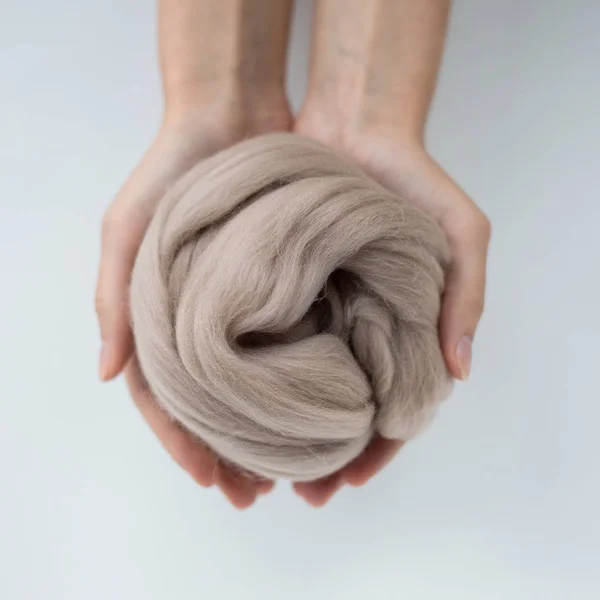Close-up de bola de lã de merino marrom em mãos — Fotografia de Stock