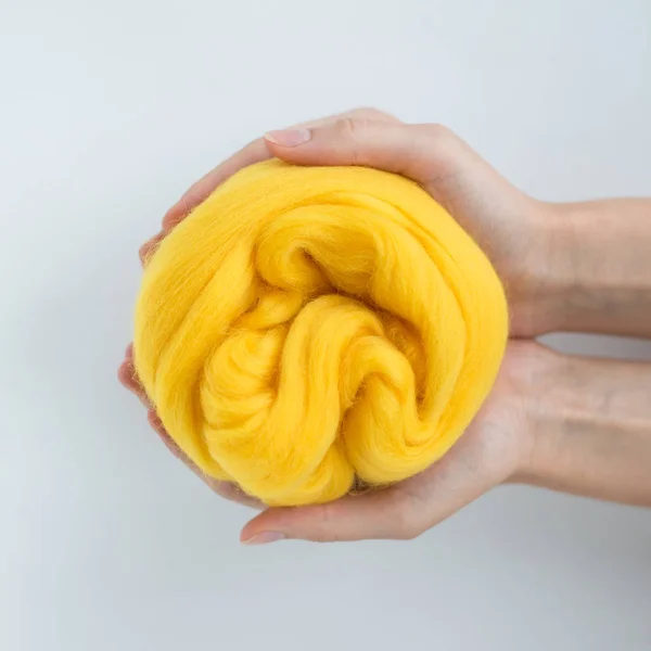 Close-up de bola de lã de merino amarelo nas mãos — Fotografia de Stock