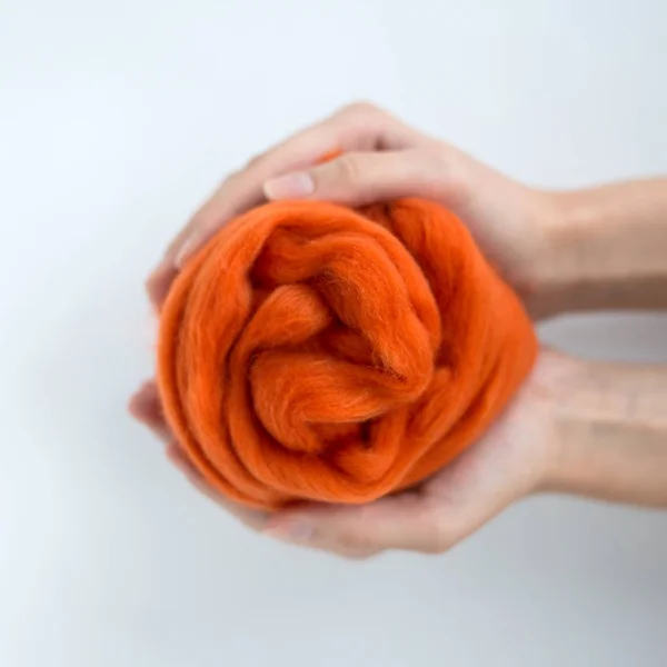 Close-up de bola de lã de merino laranja nas mãos — Fotografia de Stock