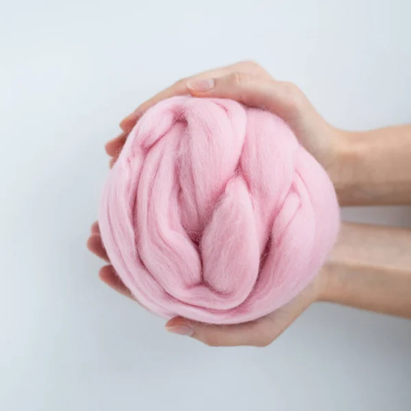 Close-up de bola de lã de merino rosa nas mãos — Fotografia de Stock