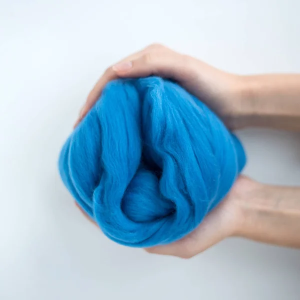 Close-up de bola de lã merino azul nas mãos — Fotografia de Stock