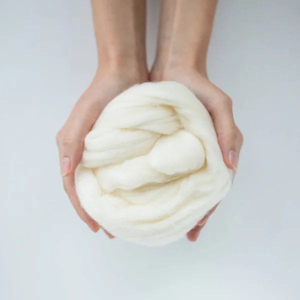 Close-up de bola de lã de merino branco nas mãos — Fotografia de Stock