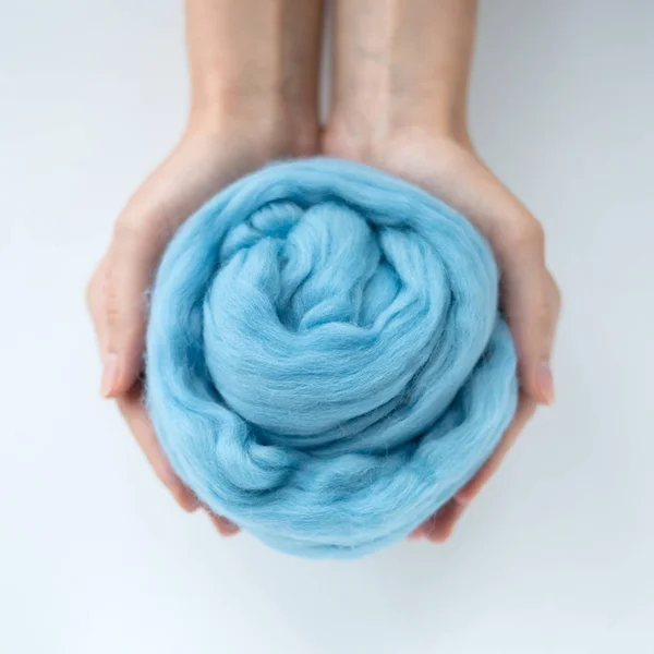 Close-up de bola de lã merino azul nas mãos — Fotografia de Stock