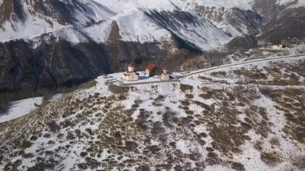 Літає над церквою в горах з видом на засніжену ущелину — стокове відео