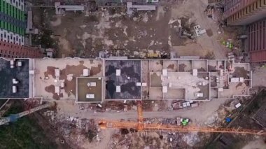 Vinçli tuğladan yapılmış yüksek katlı bir binanın çatısında insansız hava aracı manzarası.