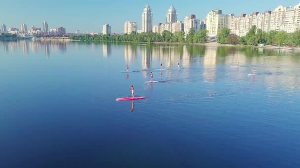 Grupo Personas Sup Surfeando Río Con Telón Fondo Ciudad Casas — Vídeos de Stock