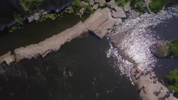 Flug über eine Schlucht mit einem Fluss mit steinernen Stromschnellen und ruhenden Menschen — Stockvideo