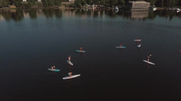 Vliegen over een groep mensen op een sup board op een rivier tegen de achtergrond van de stad — Stockvideo
