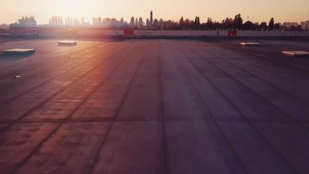Flyger över taket på ett logistikcentrums lager över lastbilar som lastar gods under en vacker solnedgång — Stockvideo