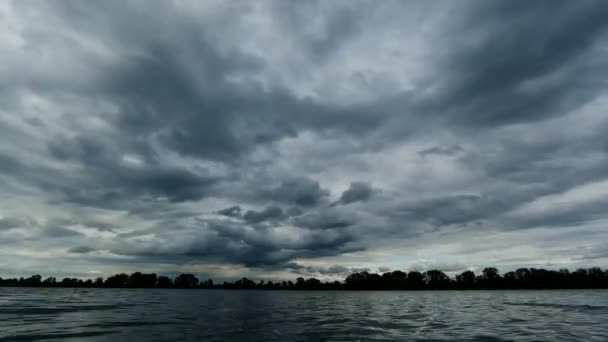 Время покажет вид на реку и облака, бегущие над ней до дождя, темно-синий цвет и лес напротив — стоковое видео