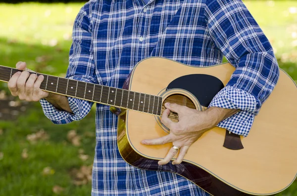 Closeup of man playing a guitar wearing a plaid shirt. — Stock Photo, Image