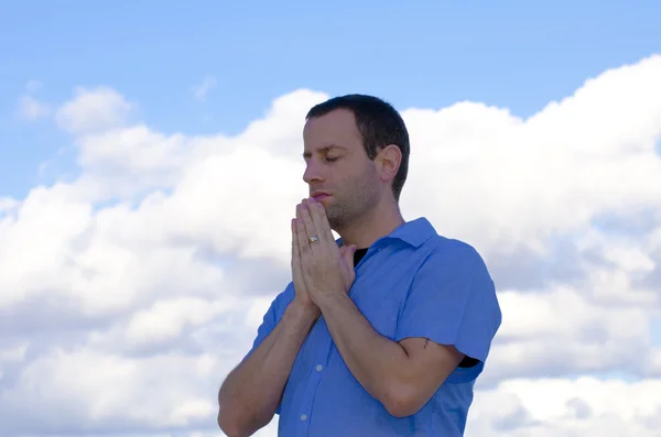Mann betet mit den Wolken im Hintergrund. Stockfoto