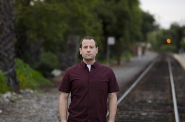 Demiryolu üzerinde ciddi sert ifade duran adamla yalnız izler.