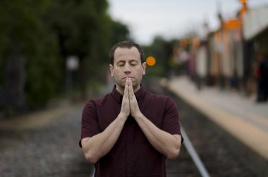 Adam tek başına bir tren durağında dua.